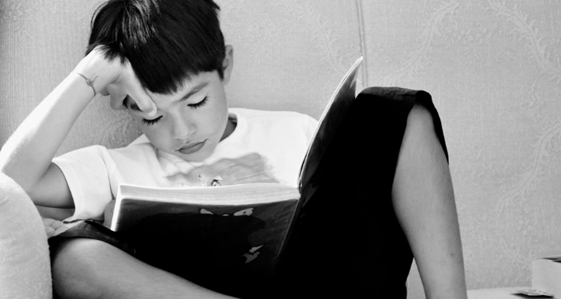 Child sitting on a couch reading a book