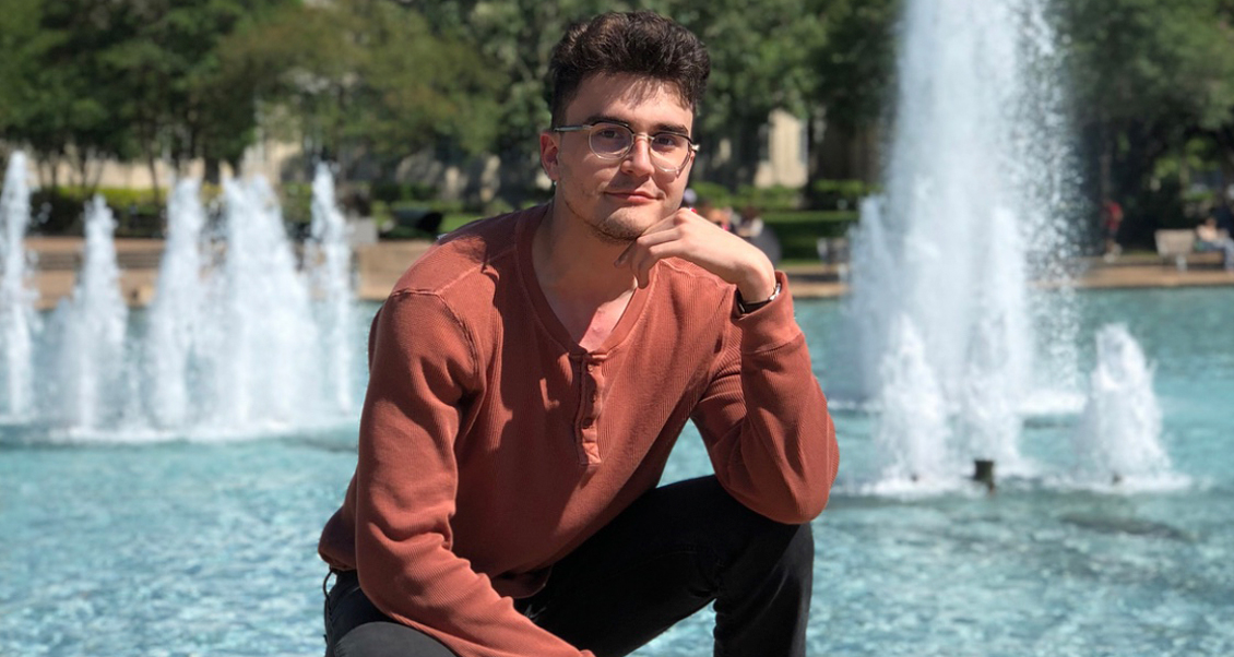 Mr. Pavel Petrov crouching in front of the UH Cullen Plaza Fountain