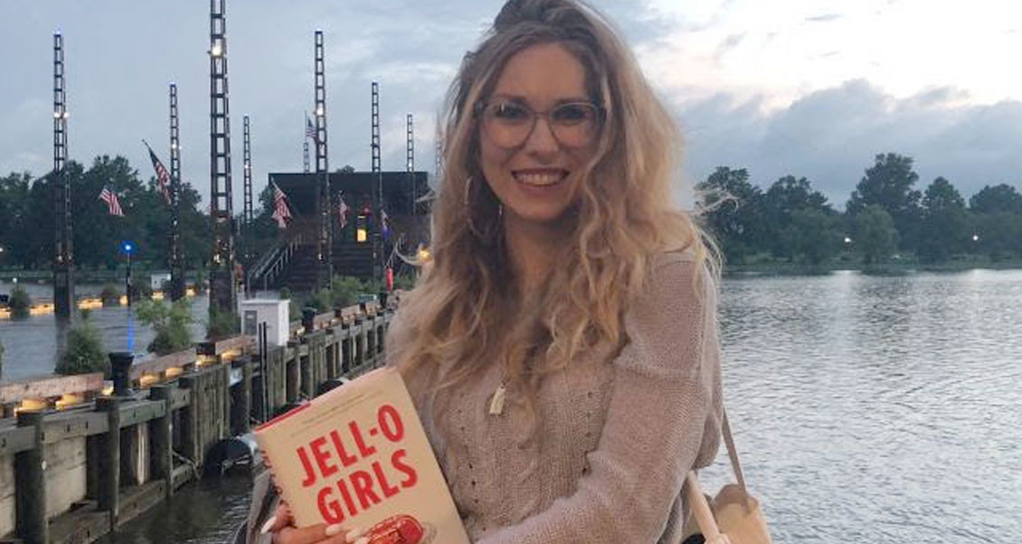 Ms. Rowbottom at a pier holding her book on her right hand side