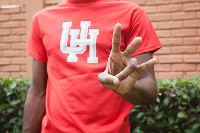 Student in a UH T-shirt flashing the Coog sign