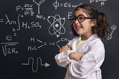 Girl with brown hair and glasses at a blackboard with numbers and letters