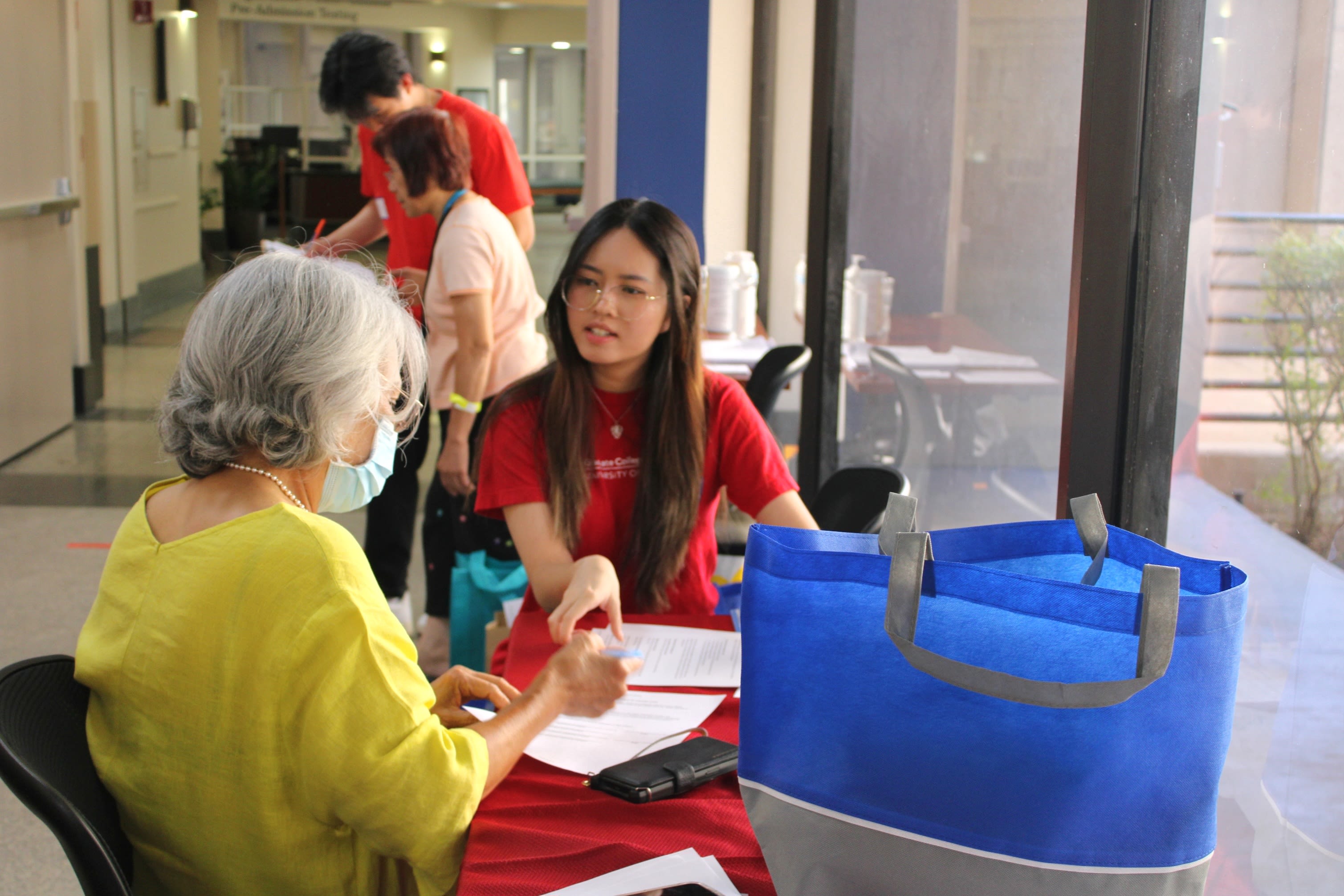 Older woman with mask speaking with university student