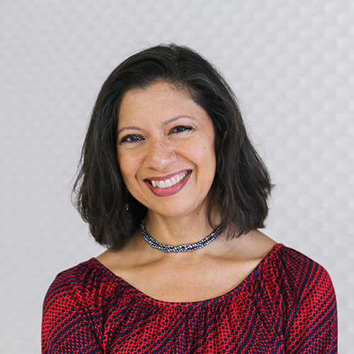 Portrait of a Hispanic woman smiling with dark shoulder length hair wearing a necklace and a red blouse